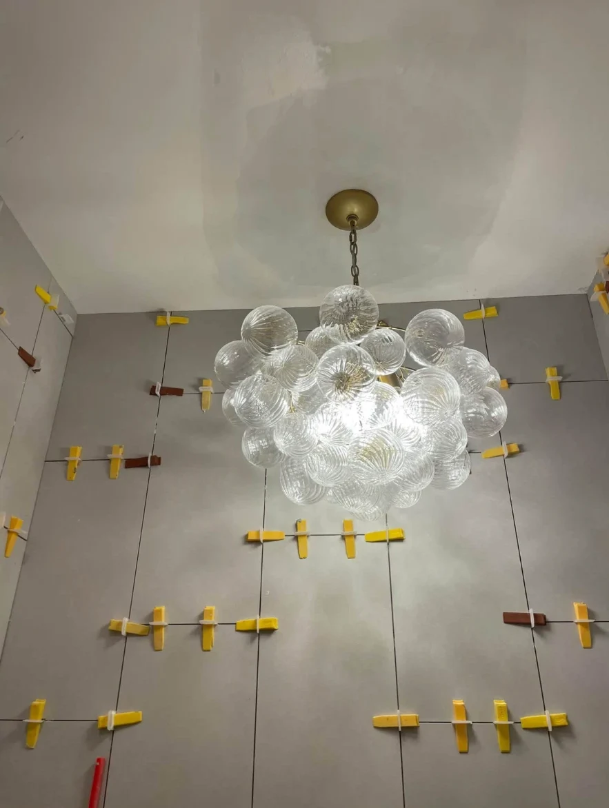 Glass bubble chandelier installed above large-format tile